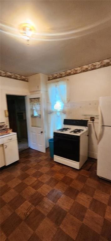 423 S Minnesota Ave, Columbus, KS 66725 - kitchen with white appliances, dark floors, white cabinets, and light countertops
