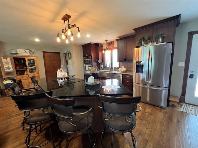 605 Queen St, King City, MO 64463 - kitchen featuring stainless steel appliances, dark wood finished floors, hanging light fixtures, a center island, and a kitchen breakfast bar