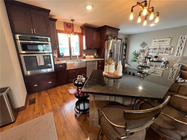 605 Queen St, King City, MO 64463 - kitchen featuring a sink, stainless steel appliances, light wood-type flooring, a kitchen breakfast bar, and pendant lighting