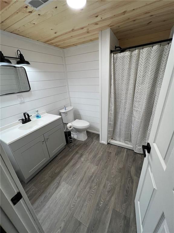 605 Queen St, King City, MO 64463 - bathroom with wooden ceiling, vanity, toilet, wood finished floors, and curtained shower