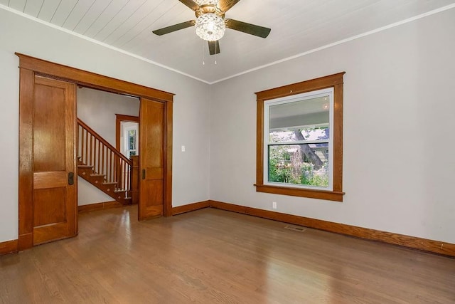 812 E Wabash St, Olathe, KS 66061 - spare room featuring wood finished floors, stairway, ceiling fan, and crown molding