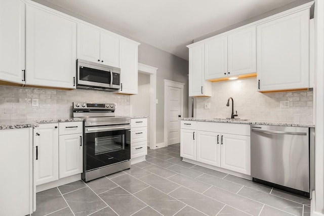 812 E Wabash St, Olathe, KS 66061 - kitchen with appliances with stainless steel finishes, backsplash, white cabinets, and light stone counters