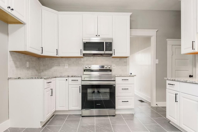 812 E Wabash St, Olathe, KS 66061 - kitchen featuring appliances with stainless steel finishes, light stone counters, white cabinetry, and decorative backsplash