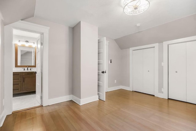 812 E Wabash St, Olathe, KS 66061 - unfurnished bedroom with lofted ceiling, light wood-type flooring, multiple closets, and connected bathroom
