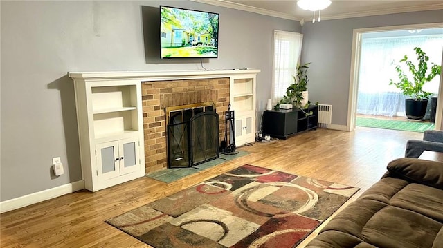1146 S Willow St, Ottawa, KS 66067 - living room with radiator heating unit, wood finished floors, ornamental molding, baseboards, and a brick fireplace