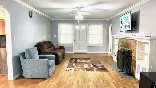 1146 S Willow St, Ottawa, KS 66067 - living area with arched walkways, wood finished floors, a fireplace, ceiling fan, and crown molding