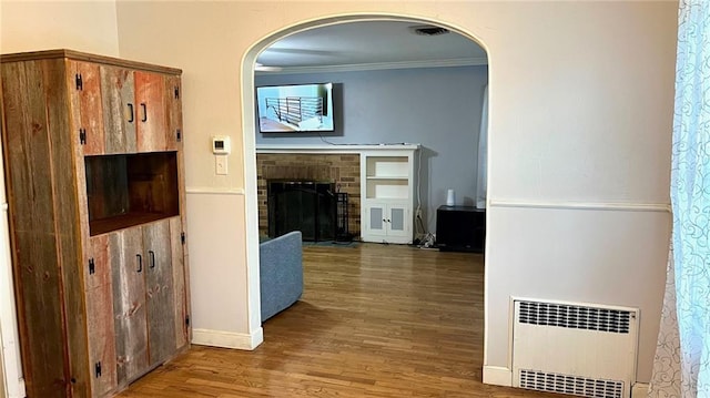 1146 S Willow St, Ottawa, KS 66067 - corridor with radiator heating unit, wood finished floors, arched walkways, crown molding, and baseboards