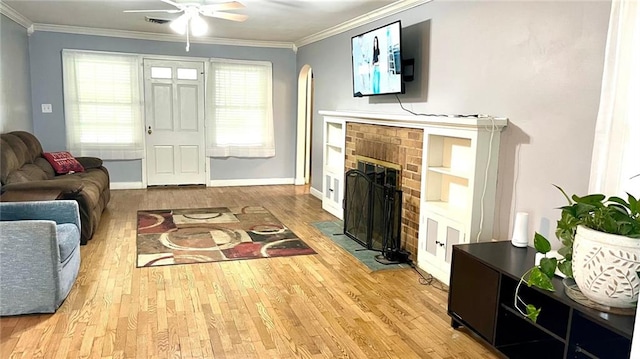 1146 S Willow St, Ottawa, KS 66067 - living area featuring wood finished floors, ornamental molding, arched walkways, a brick fireplace, and ceiling fan
