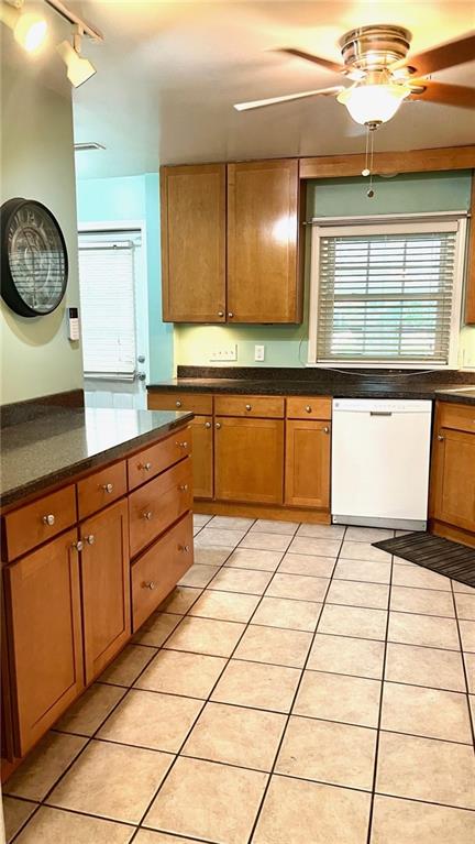 1146 S Willow St, Ottawa, KS 66067 - kitchen featuring dishwasher, a ceiling fan, dark countertops, light tile patterned floors, and brown cabinets