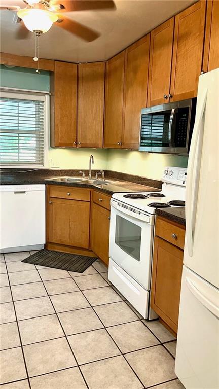 1146 S Willow St, Ottawa, KS 66067 - kitchen featuring white appliances, brown cabinets, a sink, dark countertops, and light tile patterned floors