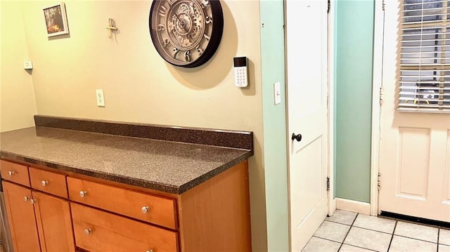 1146 S Willow St, Ottawa, KS 66067 - kitchen with dark countertops, light tile patterned flooring, and brown cabinets