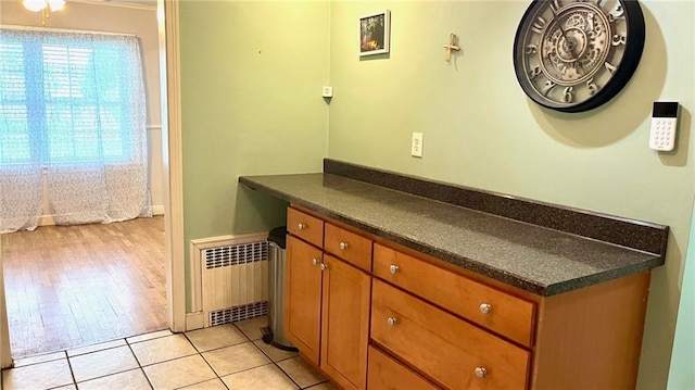1146 S Willow St, Ottawa, KS 66067 - kitchen featuring radiator, dark countertops, brown cabinetry, and light tile patterned flooring