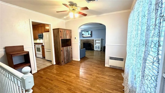 1146 S Willow St, Ottawa, KS 66067 - corridor with radiator, arched walkways, ornamental molding, light wood-style flooring, and baseboards