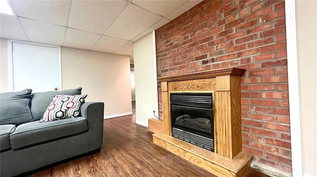 1146 S Willow St, Ottawa, KS 66067 - living area featuring wood finished floors, a glass covered fireplace, a drop ceiling, and baseboards