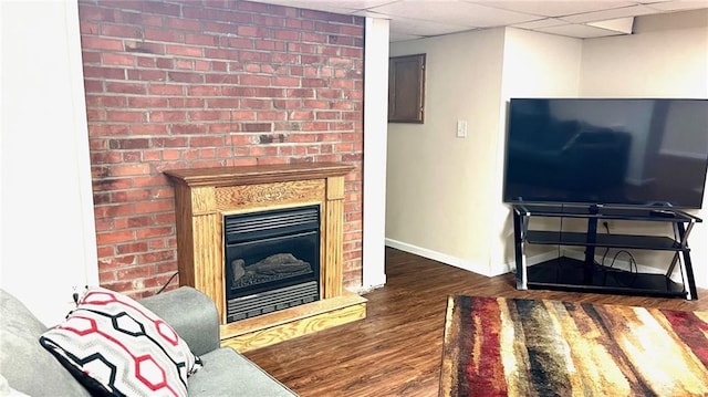 1146 S Willow St, Ottawa, KS 66067 - living room featuring wood finished floors, baseboards, a glass covered fireplace, and a paneled ceiling