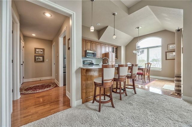 12207 England St, Overland Park, KS 66213 - kitchen featuring stainless steel microwave, a kitchen bar, stove, baseboards, and light wood finished floors