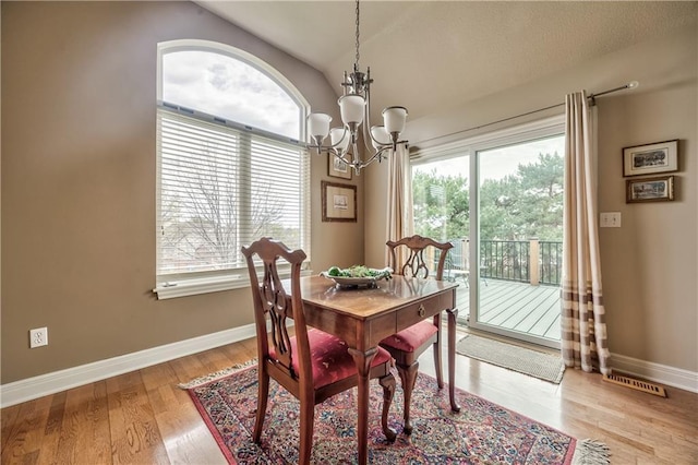 12207 England St, Overland Park, KS 66213 - dining area with a chandelier, baseboards, healthy amount of natural light, lofted ceiling, and light wood-style flooring