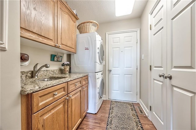 12207 England St, Overland Park, KS 66213 - laundry room featuring stacked washer and clothes dryer, cabinet space, and light wood-style flooring