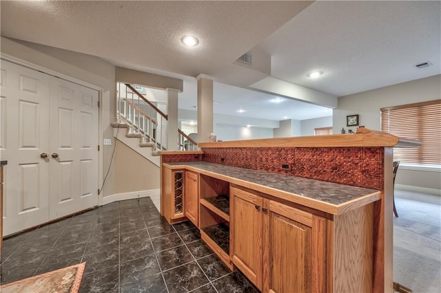 12207 England St, Overland Park, KS 66213 - kitchen with baseboards, brown cabinetry, dark countertops, recessed lighting, and a textured ceiling