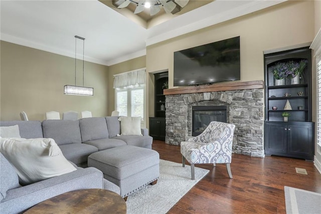 16570 S Ingrid St, Gardner, KS 66030 - living area featuring crown molding, dark wood-type flooring, a stone fireplace, ceiling fan, and built in features