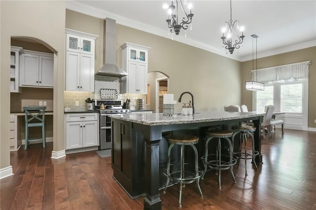 16570 S Ingrid St, Gardner, KS 66030 - kitchen featuring double oven range, wall chimney range hood, arched walkways, backsplash, and a breakfast bar area