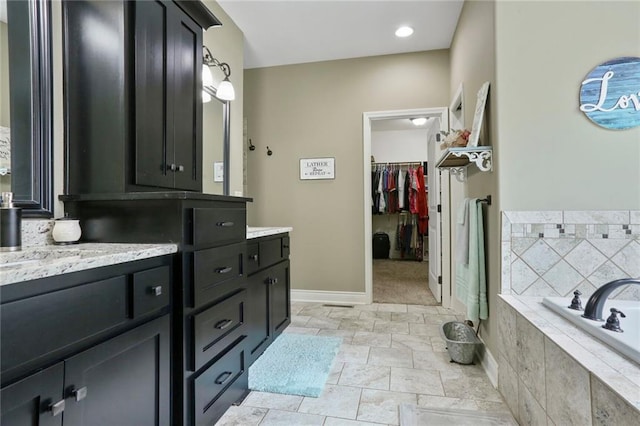 16570 S Ingrid St, Gardner, KS 66030 - full bath featuring vanity, a garden tub, baseboards, a walk in closet, and stone finish floors