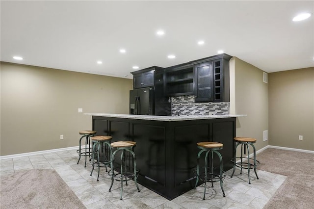 16570 S Ingrid St, Gardner, KS 66030 - indoor dry bar with black fridge with ice dispenser, decorative backsplash, recessed lighting, and baseboards