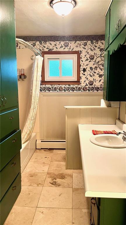 1441 S Maple St, Ottawa, KS 66067 - bathroom featuring baseboard heating, vanity, wallpapered walls, shower / bath combo with shower curtain, and a wainscoted wall