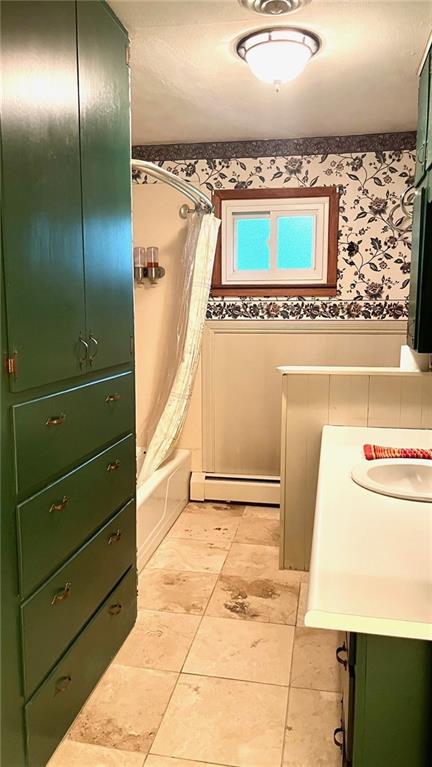 1441 S Maple St, Ottawa, KS 66067 - bathroom with a baseboard heating unit, shower / bath combination with curtain, vanity, and wallpapered walls