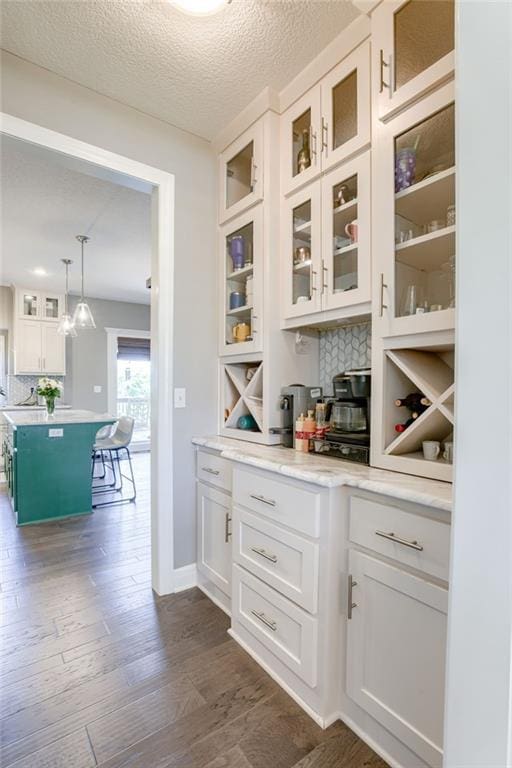 8721 N Mersington Ave, Kansas City, MO 64156 - bar with decorative backsplash, dark wood-type flooring, a textured ceiling, and decorative light fixtures
