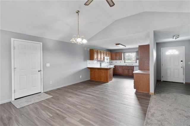 12 SW 365th Rd, Warrensburg, MO 64093 - kitchen featuring lofted ceiling, a peninsula, brown cabinetry, wood finished floors, and open floor plan