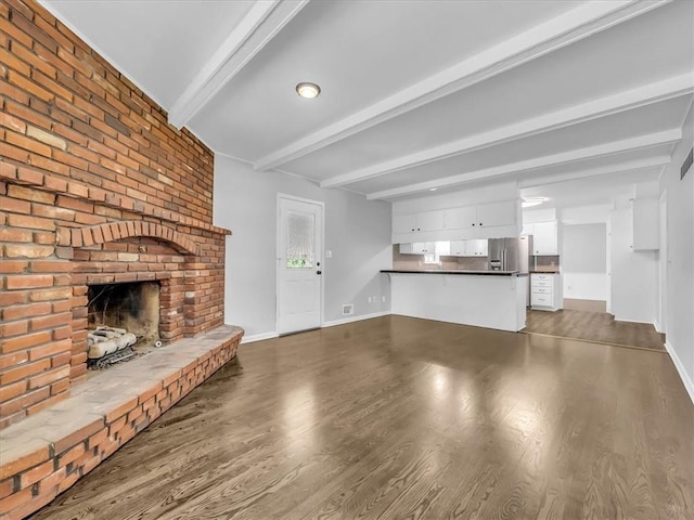 15378 E 45th St S, Independence, MO 64055 - unfurnished living room featuring beamed ceiling, a brick fireplace, wood finished floors, and baseboards