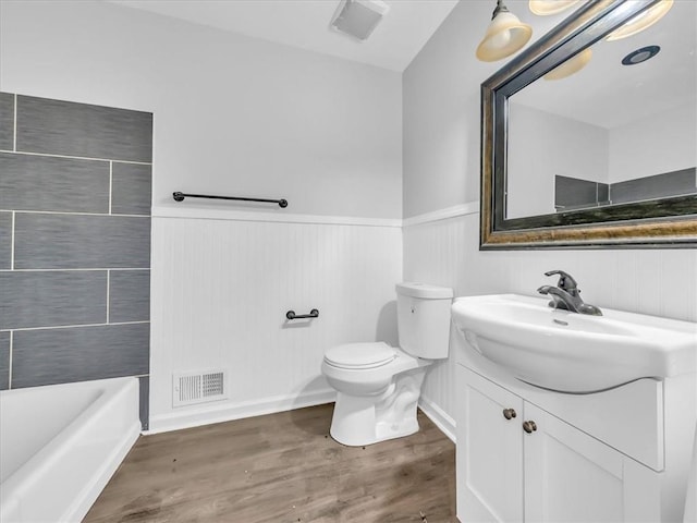15378 E 45th St S, Independence, MO 64055 - bathroom with vanity, a wainscoted wall, a tub, toilet, and wood finished floors