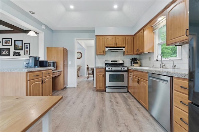 12411 W 100th St, Lenexa, KS 66215 - kitchen featuring appliances with stainless steel finishes, light wood finished floors, decorative backsplash, pendant lighting, and under cabinet range hood