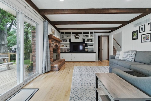 12411 W 100th St, Lenexa, KS 66215 - living room featuring a fireplace, light wood-style flooring, beamed ceiling, and stairs