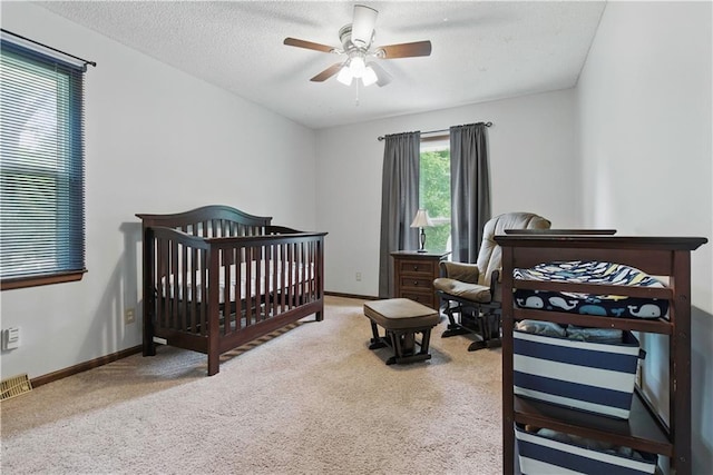 12411 W 100th St, Lenexa, KS 66215 - bedroom with carpet floors, a ceiling fan, a crib, and a textured ceiling