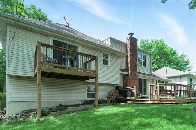 12411 W 100th St, Lenexa, KS 66215 - rear view of property featuring a chimney, a lawn, a wooden deck, and a shingled roof