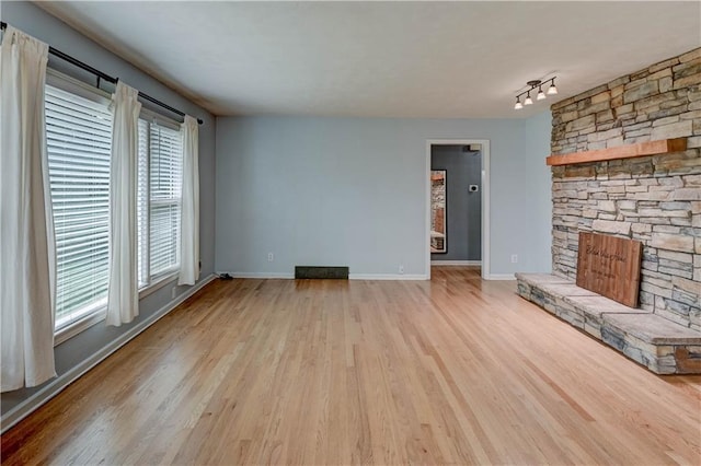 7907 Elm Ave, Raytown, MO 64138 - unfurnished living room featuring a fireplace, wood finished floors, and rail lighting