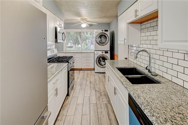 7907 Elm Ave, Raytown, MO 64138 - kitchen with appliances with stainless steel finishes, stacked washer / drying machine, ceiling fan, and white cabinetry