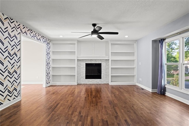 12001 S Hagan St, Olathe, KS 66062 - unfurnished living room featuring baseboards, wood finished floors, a ceiling fan, a textured ceiling, and a fireplace
