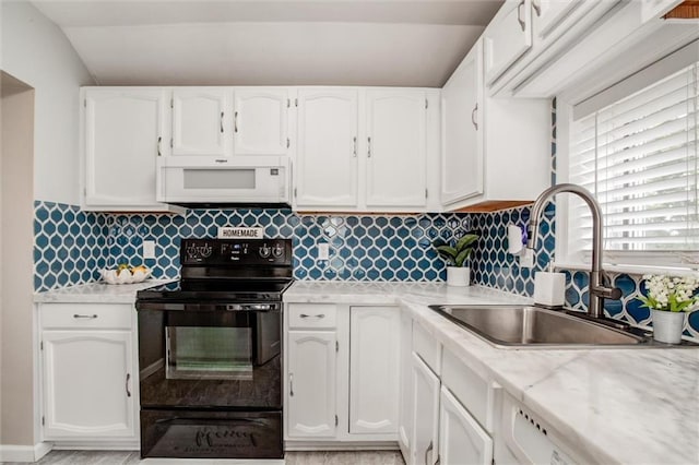 6005 NE 50th St, Kansas City, MO 64119 - kitchen featuring white microwave, black range with electric stovetop, white cabinets, and vaulted ceiling