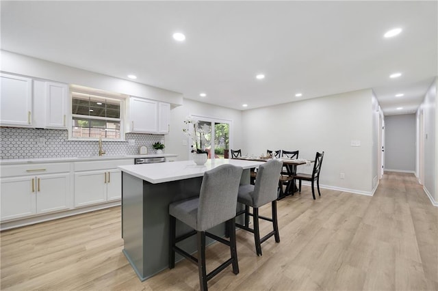 513 Forestglen Ln, Lansing, KS 66043 - kitchen with a kitchen bar, a center island, white cabinets, backsplash, and light wood finished floors