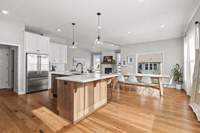 1517 SW Arbor Creek Dr, Lees Summit, MO 64082 - kitchen with appliances with stainless steel finishes, a sink, light wood-style floors, light countertops, and a fireplace