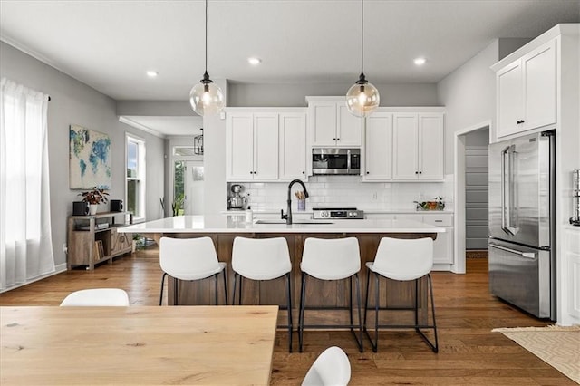1517 SW Arbor Creek Dr, Lees Summit, MO 64082 - kitchen featuring stainless steel appliances, an island with sink, light countertops, a sink, and white cabinets