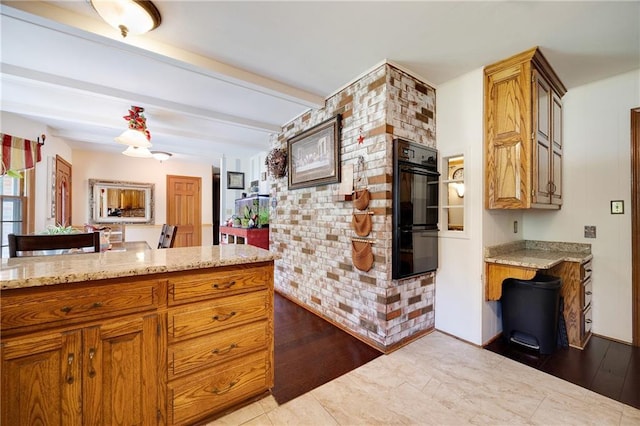 3814 S Outer Belt Rd, Oak Grove, MO 64075 - kitchen featuring brown cabinetry, beamed ceiling, light stone counters, wood finished floors, and an accent wall