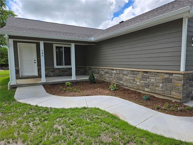 904 N 9th St, Neodesha, KS 66757 - view of exterior entry featuring stone siding, a porch, and roof with shingles