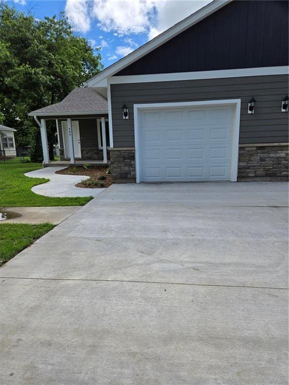 904 N 9th St, Neodesha, KS 66757 - view of front of home featuring stone siding, driveway, and a garage