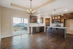 18408 Rock Creek Dr N, Smithville, MO 64089 - kitchen featuring stainless steel microwave, light countertops, a chandelier, decorative light fixtures, and dark brown cabinetry