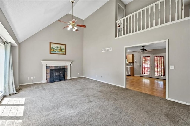 701 NE Hunters Cir, Blue Springs, MO 64014 - unfurnished living room with carpet floors, ceiling fan, high vaulted ceiling, a tile fireplace, and french doors