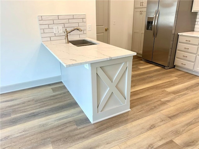 2006 Fountain Creek Dr, Saint Joseph, MO 64504 - kitchen featuring a sink, stainless steel refrigerator with ice dispenser, light wood finished floors, light stone counters, and a peninsula